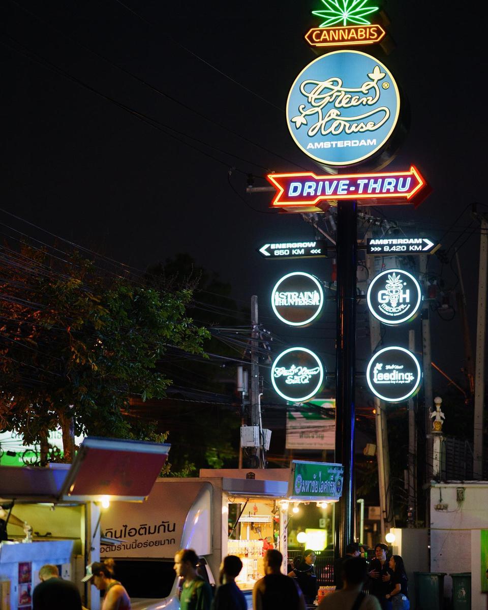 Green House Amsterdam illuminated roadside branding alongside Strain Hunters and GHS branding
